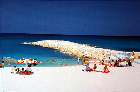 algida şemsiyesiyle plajda oturan insanlar ve deniz girenler